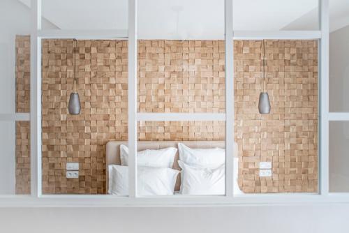 a bed with white pillows and a brick wall at Suite Georgia in Villeurbanne