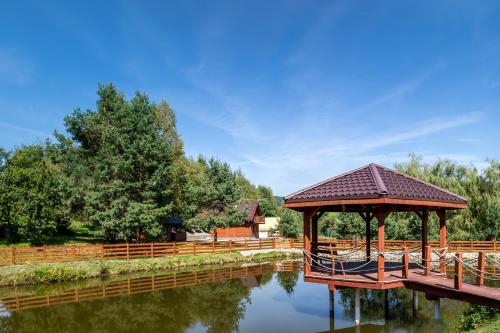 a gazebo next to a river with a bridge at Glamping Pod Gwiazdami in Pietrusza Wola