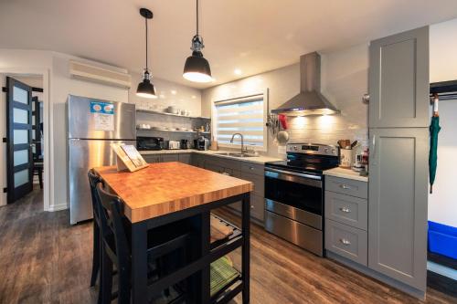 a kitchen with stainless steel appliances and a wooden table at Auberge Sous les Arbres in Gaspé