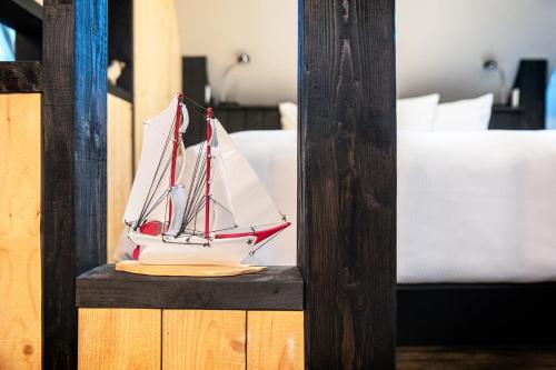 a toy boat sitting on a shelf next to a bed at Auberge Sous les Arbres in Gaspé