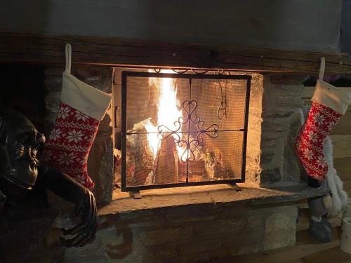a fireplace with two christmas socks and a fire at Chalet 7 Luxury Chalet with Cinema room in Crans-Montana