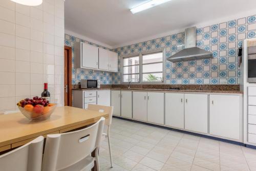 a kitchen with white cabinets and a bowl of fruit on a table at BRESSOL DELUXE Apartments in Port de Pollensa