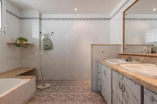 a bathroom with two sinks and a tub and a mirror at BRESSOL DELUXE Apartments in Port de Pollensa