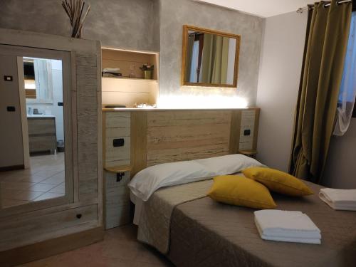 a bedroom with a bed with yellow pillows and a mirror at Bed & Breakfast Ca'Bassano in Bassano del Grappa