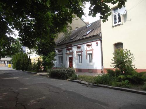 una casa blanca con techo negro y una calle en Pension U akátu en Praga