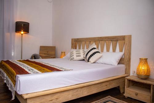 a bedroom with a wooden bed with pillows on it at Ndar Ndar House in Saint-Louis