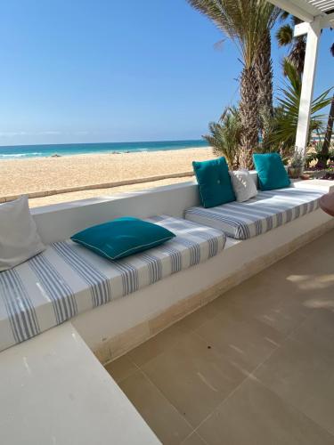 a row of pillows sitting on a bench on the beach at Villa Nº25b Alfredo Marchetti suites on the beach Praia di Chaves in Cabeçadas