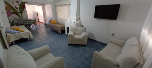 Sala de estar con 2 sofás blancos y TV en CASA VERDE II en Carhué