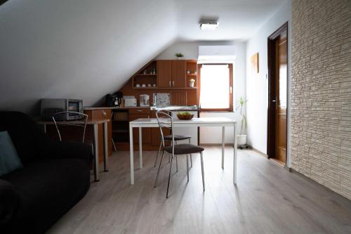 a living room with a table and chairs and a kitchen at Marietta Apartman in Hévíz