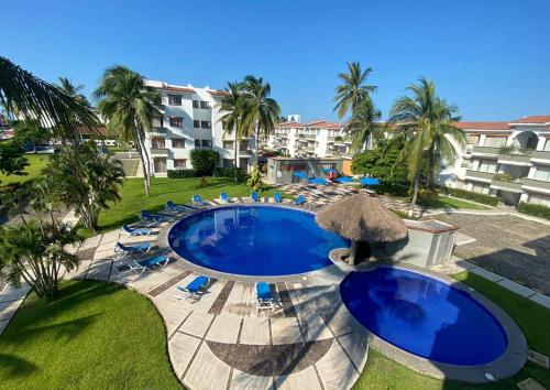 an outdoor swimming pool with chairs and an umbrella at hermoso condominio suites las palmas con alberca in Manzanillo
