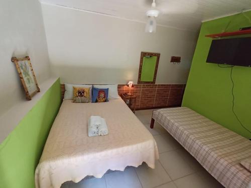 a bedroom with a green bed and a tv at Hospedagem Recanto dos Ties in Abraão