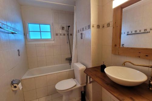 a bathroom with a sink and a toilet and a tub at Appartement avec terrasse ensoleillée in Gruyères