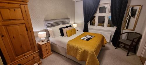 a small bedroom with a bed with a yellow blanket at The Howbeck & The Retreat Central location, incl off-site Health Club and parking EV point available, GREAT DEALS ON in Windermere