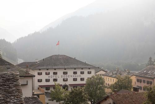 a building with a flag on top of a town at Hôtel Bodenhaus in Splügen
