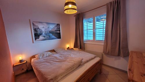 a bedroom with a bed and a window with two lamps at Appartement avec terrasse ensoleillée in Gruyères