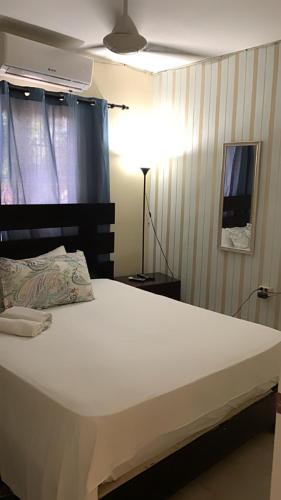 a large white bed in a room with a lamp at CENTRICO con wifi y luz incluido la romana in La Romana