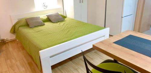 a bedroom with a bed with green sheets and a table at Studio Jadro in Selce