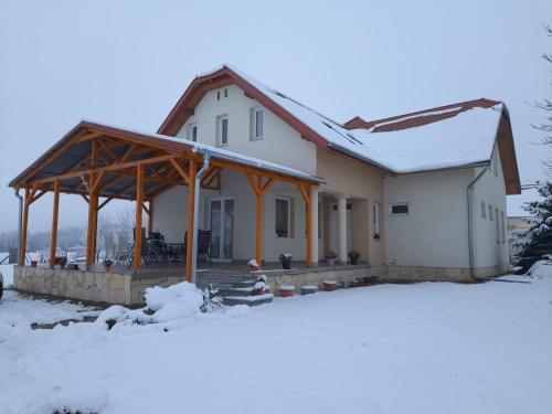 a house with a covered porch in the snow at Anna Vendégház Szeleste in Szeleste