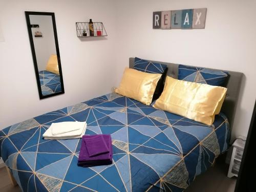 a bedroom with a blue bed with yellow and purple pillows at Charmant appartement T2 dans villa avec en supplément spa extérieur de mai à septembre in Laveyron