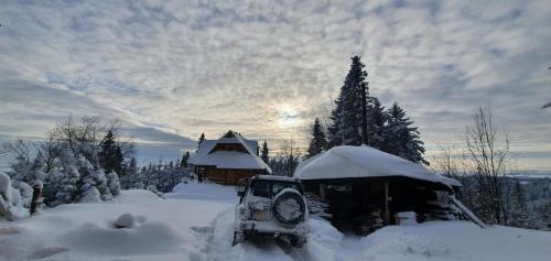 a snow covered yard with a house and a bulldozer at Domek w Górach- Bacówka u Dudka in Nowy Targ