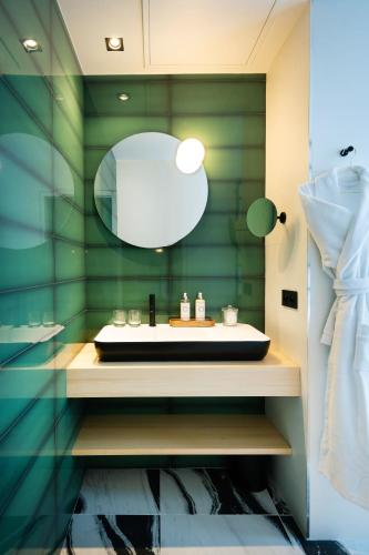 a green bathroom with a sink and a mirror at Hôtel Amoi Paris in Paris