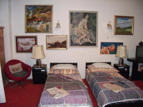 2 Betten in einem Zimmer mit Gemälden an der Wand in der Unterkunft Fónagy és Walter Vendég- és Borház in Vác