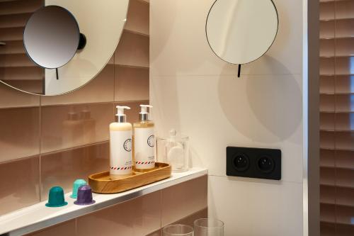a bathroom with two bottles on a shelf with two mirrors at Hôtel Amoi Paris in Paris