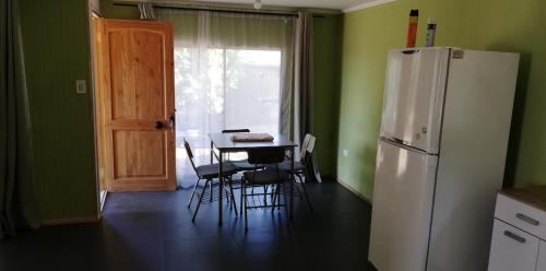 a kitchen with a table and a white refrigerator at Cabañas El Toro - Radal Siete Tazas in Molina