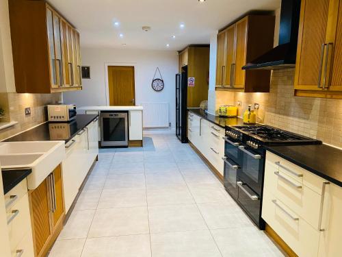 a large kitchen with wooden cabinets and black appliances at Castlebar in Great Singleton