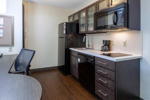 a kitchen with a sink and a black refrigerator at Candlewood Suites Kalamazoo by IHG in Kalamazoo