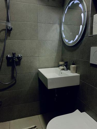 uma casa de banho com um lavatório, um espelho e um WC. em Lovely Apartment at the city of Tirana em Tirana