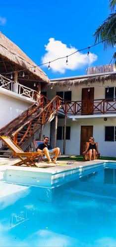 two men are sitting in a swimming pool next to a house at Hotel Xa´an Bacalar in Bacalar