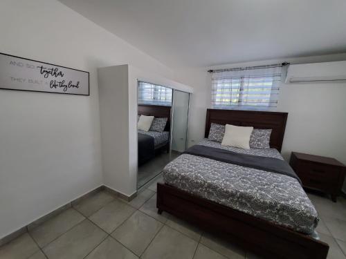 1 dormitorio con cama y espejo. en Aguadilla Sunrise apt with AC WIFI 8 minute walk from Crashboat beach en Aguadilla
