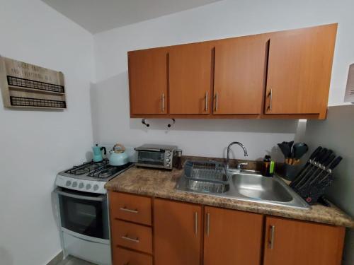 a kitchen with a sink and a stove and cabinets at Aguadilla Sunrise apt with AC WIFI 8 minute walk from Crashboat beach in Aguadilla