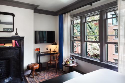 a bedroom with a fireplace and a desk and windows at The High Line Hotel in New York