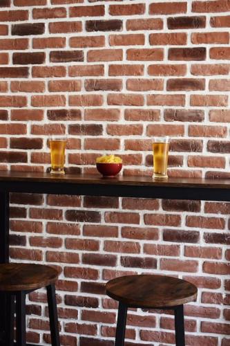 un mur en briques avec deux verres et deux tabourets dans l'établissement Studio Championnet, balcon, haut confort, à Grenoble