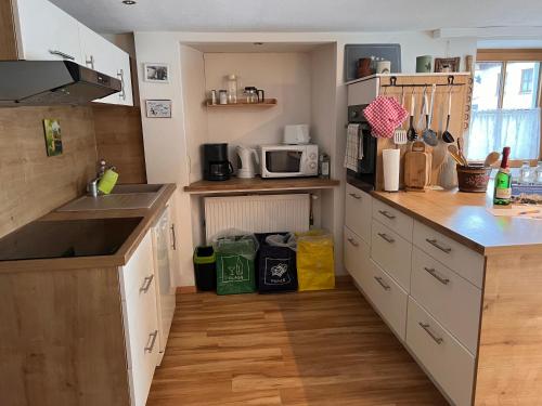 a kitchen with white cabinets and a wooden floor at Ferienhaus Gertrud in Nesselwängle