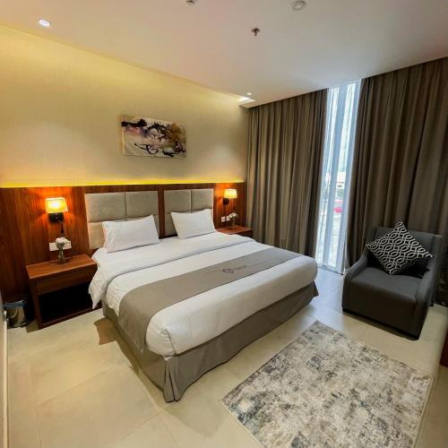 a bedroom with a large bed and a chair at سيتيز إن للشقق المخدومة in Yanbu