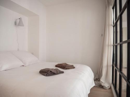 Una cama blanca con un par de toallas. en L'ORANGERAIE Appartement design en plein centre, en Castres