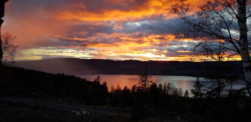 a sunset over a body of water with a cloudy sky at Mjøshytte in Stange