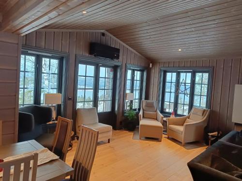 a living room filled with furniture and windows at Mjøshytte in Stange
