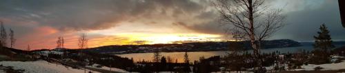 a sunset over a lake with a cloudy sky at Mjøshytte in Stange