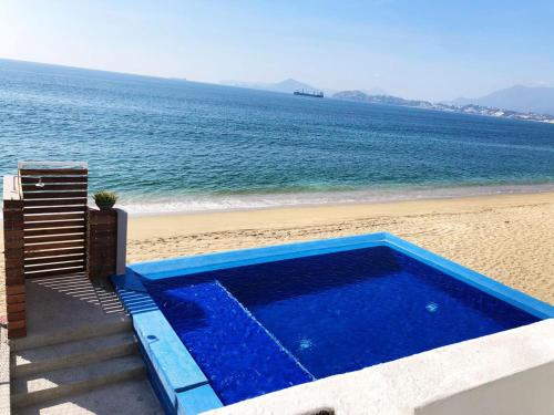 a swimming pool on the beach next to the ocean at INCREIBLE DEPARTAMENTO A PIE DE PLAYA EN MANZANILLO, COMPLETAMENTE NUEVO in Manzanillo