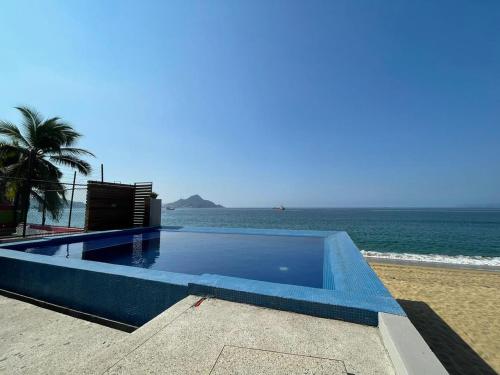een blauw zwembad naast het strand bij INCREIBLE DEPARTAMENTO A PIE DE PLAYA EN MANZANILLO, COMPLETAMENTE NUEVO in Manzanillo