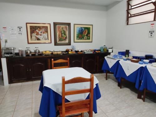 a kitchen with two tables with blue and white table cloth at Hotel Js in Alfenas