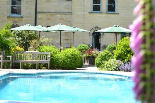 a swimming pool with two chairs and umbrellas at Beechfield House in Beanacre