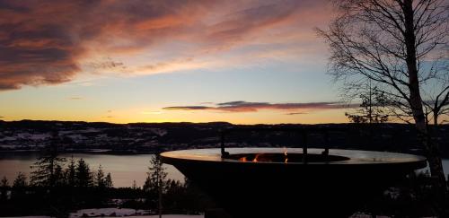 a hot tub with a fire in the sunset at Mjøshytte in Stange