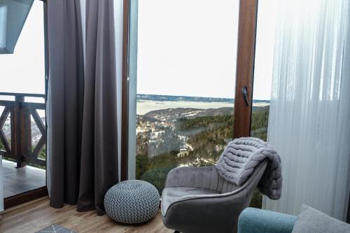 ein Wohnzimmer mit einem Stuhl und einem großen Fenster in der Unterkunft Vila Planinsko Blago in Kopaonik