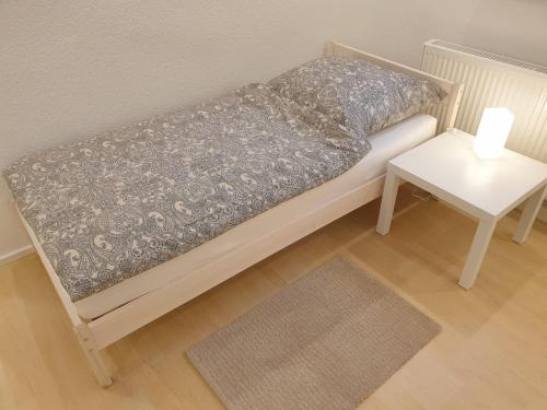 Schelklingenにある2 Zimmer Apartment im UG Schelklingen Biosphärenreservat Schwäbische Albのナイトスタンドとテーブル付きの小さなベッド