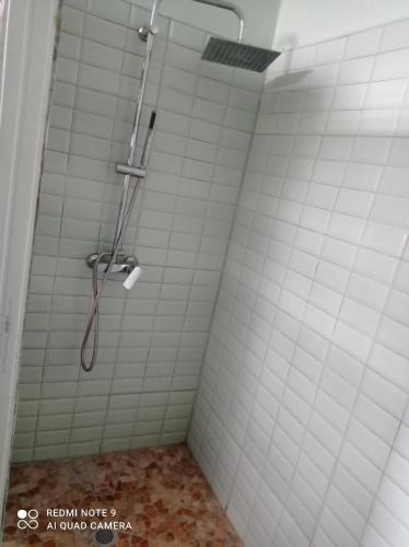 a shower in a bathroom with white tiles at La Marie-Galantaise dans la nature in Beaurenom
